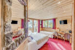 Experience the charm of this cozy bedroom featuring wooden walls and ceilings, creating a warm and inviting atmosphere.