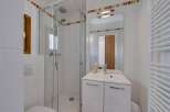 This modern bathroom features a sleek glass shower, a stylish vanity with a mirror, and a convenient toilet.