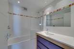 This modern bathroom features a sleek design with white tiles and a glass shower enclosure.