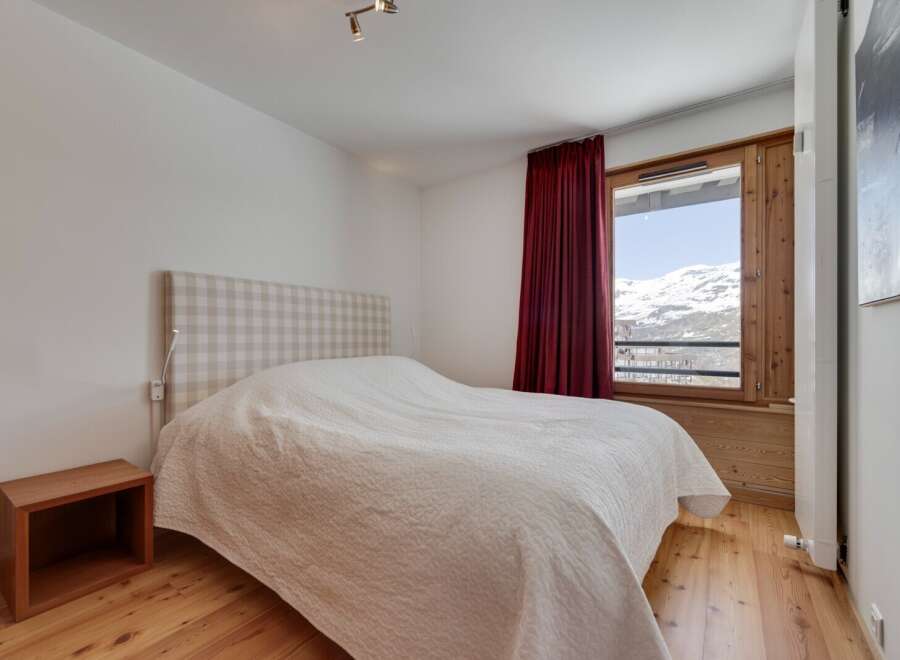 This cozy bedroom features a comfortable bed with a checkered headboard and a warm, inviting atmosphere.