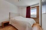 This cozy bedroom features a comfortable bed with a checkered headboard and a warm, inviting atmosphere.