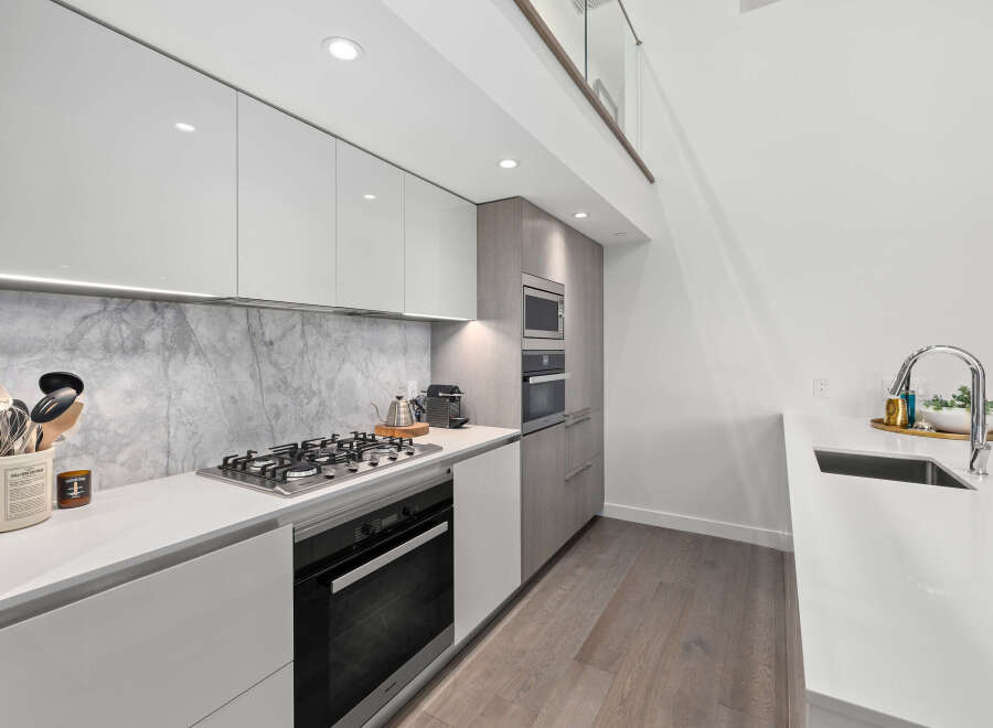 Experience modern luxury in this stunning kitchen! Featuring sleek white cabinetry, a marble backsplash, and high-end appliances, this space is perfect for both cooking and entertaining.