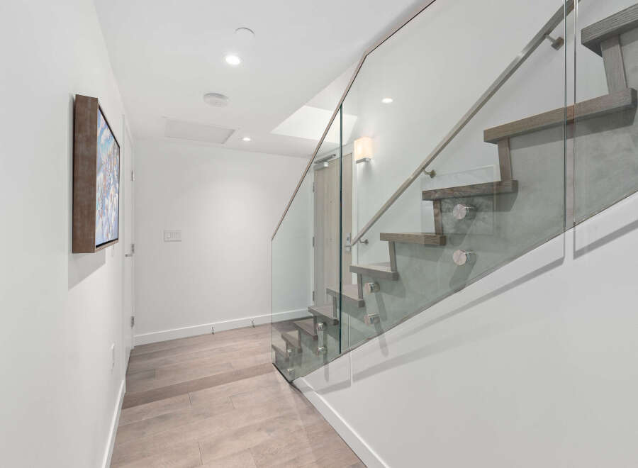 This stunning property features a modern staircase with glass railings, creating an open and airy feel.