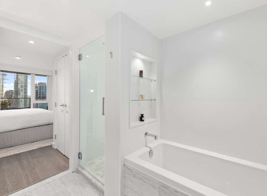 Step into luxury with this stunning bathroom, featuring a sleek glass shower and a relaxing bathtub.