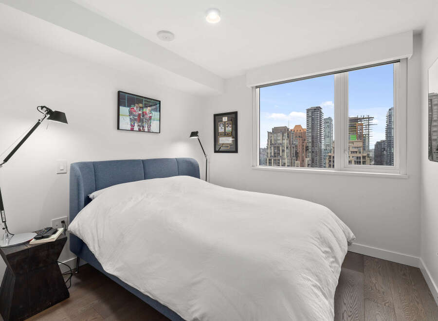This modern bedroom offers stunning city views through a large window.