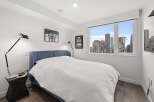 This modern bedroom offers stunning city views through a large window.