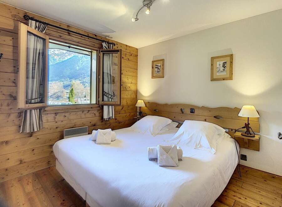 Experience the charm of this cozy bedroom, featuring a comfortable bed and a stunning view of the mountains.