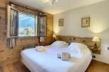 Experience the charm of this cozy bedroom, featuring a comfortable bed and a stunning view of the mountains.