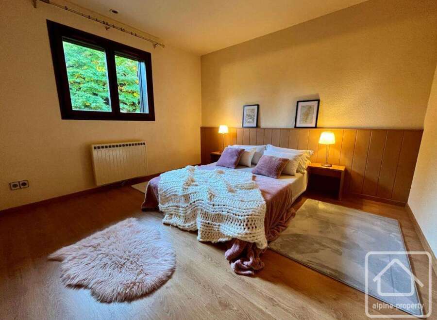 Discover the charm of this cozy bedroom, featuring a comfortable bed with plush pillows and a warm, inviting ambiance.