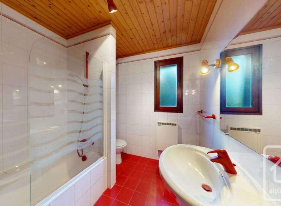 This charming bathroom features a unique combination of red tile flooring and a wooden ceiling, creating a warm and inviting atmosphere.
