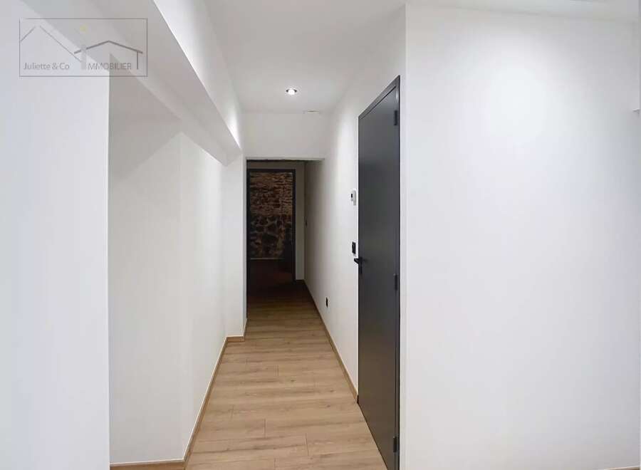 This stunning property boasts a modern hallway with sleek white walls and a warm wooden floor, creating a welcoming atmosphere.