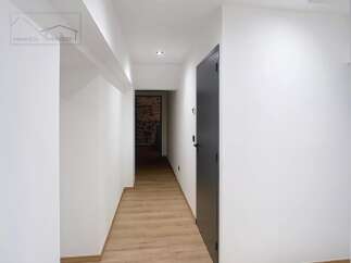 This stunning property boasts a modern hallway with sleek white walls and a warm wooden floor, creating a welcoming atmosphere.