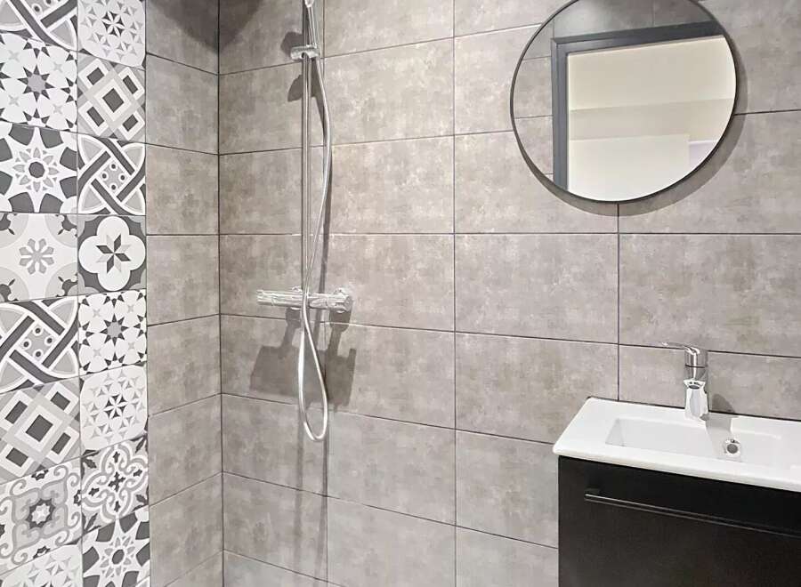 Step into a modern bathroom oasis! This stylish space features a sleek shower with a rainfall showerhead and a contemporary vanity.