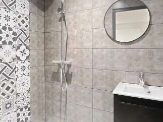 Step into a modern bathroom oasis! This stylish space features a sleek shower with a rainfall showerhead and a contemporary vanity.