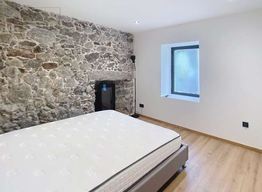 Discover the charm of this unique bedroom featuring a stunning stone wall that adds character and warmth.