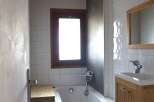 Discover this charming bathroom featuring a cozy wooden ceiling and a bright window that fills the space with natural light.