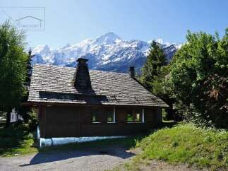 Nestled amidst the breathtaking backdrop of snow-capped mountains, this charming wooden cabin offers a serene escape.