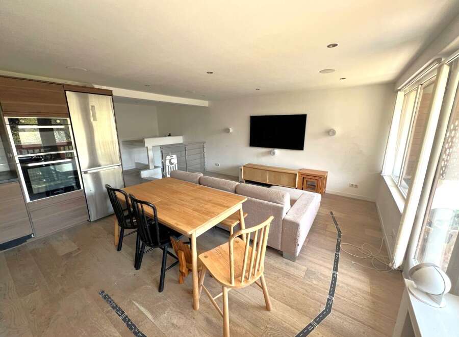 This modern living space features a stylish dining area with a wooden table and chairs, perfect for family meals or entertaining guests.