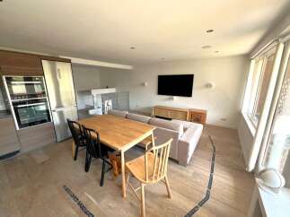 This modern living space features a stylish dining area with a wooden table and chairs, perfect for family meals or entertaining guests.