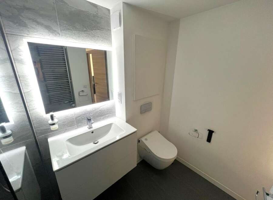 Step into a modern bathroom oasis! This stylish space features a sleek, illuminated mirror above a contemporary sink, perfect for your daily routine.