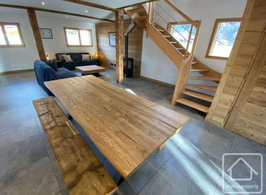This stunning property boasts a spacious living area with a beautiful wooden dining table and bench, perfect for entertaining.