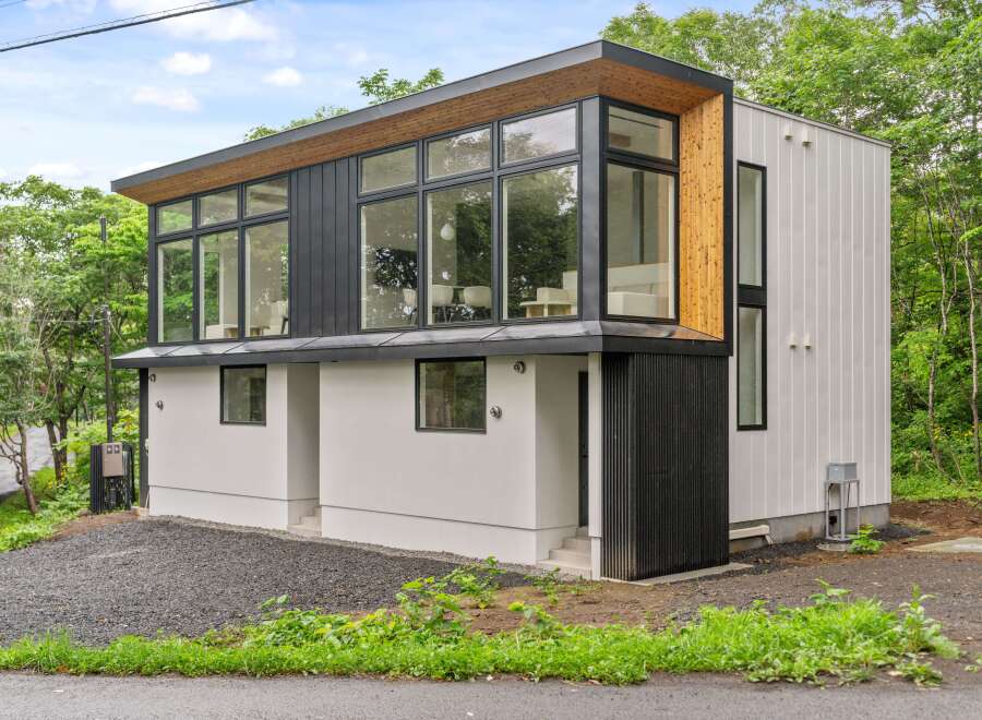 This modern architectural marvel showcases a stunning two-story design with expansive windows that flood the interior with natural light.