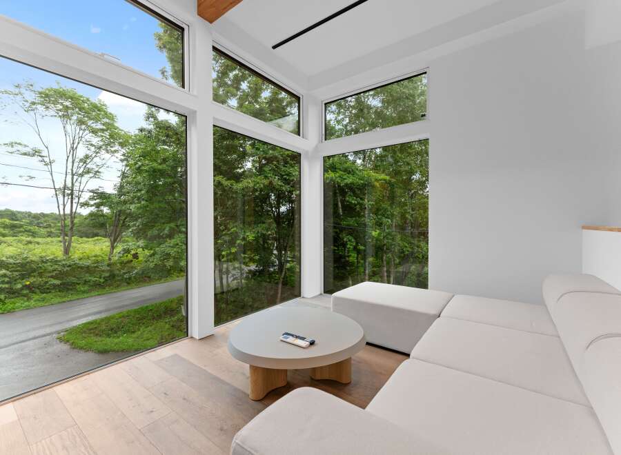 Experience modern living with this stunning property featuring expansive windows that frame breathtaking views of lush greenery.