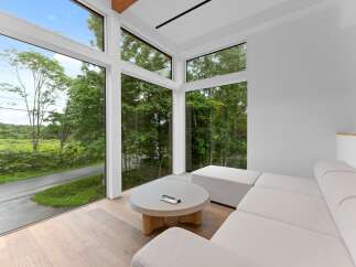 Experience modern living with this stunning property featuring expansive windows that frame breathtaking views of lush greenery.