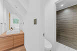 This modern bathroom features a sleek design with a wooden vanity and a minimalist sink.