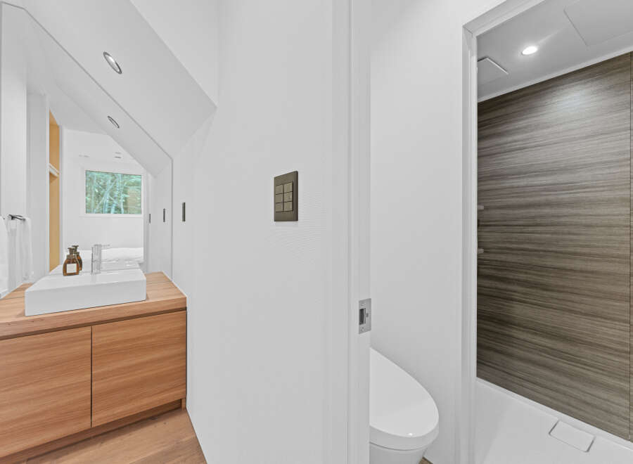 This modern bathroom features a sleek design with a wooden vanity and a minimalist sink.