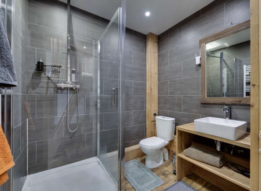 Step into this modern bathroom, featuring a sleek glass shower enclosure and stylish gray tile.