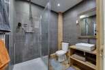 Step into this modern bathroom, featuring a sleek glass shower enclosure and stylish gray tile.