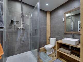 Step into this modern bathroom, featuring a sleek glass shower enclosure and stylish gray tile.