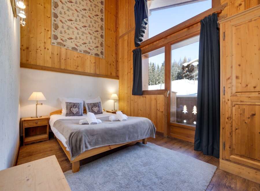 Experience the charm of this cozy bedroom, featuring a warm wooden interior and a comfortable bed.
