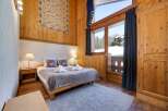 Experience the charm of this cozy bedroom, featuring a warm wooden interior and a comfortable bed.