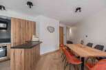 This modern kitchen and dining area boasts a sleek design with wooden cabinetry and a contrasting black countertop.