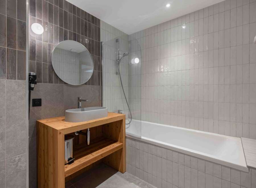 This modern bathroom boasts a sleek design with a wooden vanity and a stylish oval sink.