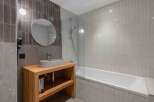 This modern bathroom boasts a sleek design with a wooden vanity and a stylish oval sink.
