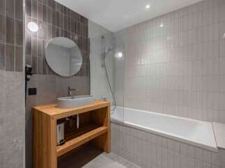 This modern bathroom boasts a sleek design with a wooden vanity and a stylish oval sink.