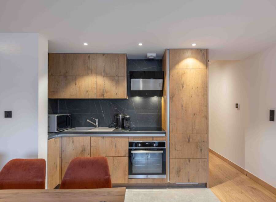 This modern kitchen boasts sleek wooden cabinetry and a stylish black backsplash, creating a sophisticated and inviting space.