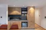 This modern kitchen boasts sleek wooden cabinetry and a stylish black backsplash, creating a sophisticated and inviting space.