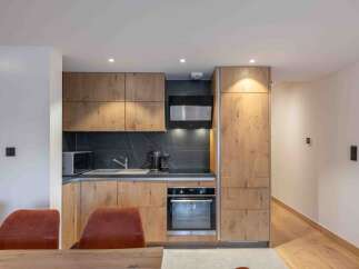 This modern kitchen boasts sleek wooden cabinetry and a stylish black backsplash, creating a sophisticated and inviting space.
