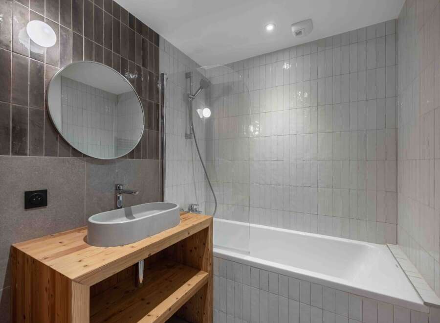 This modern bathroom features a sleek design with a wooden vanity and a stylish oval sink.