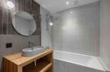 This modern bathroom features a sleek design with a wooden vanity and a stylish oval sink.
