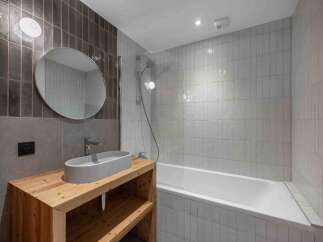 This modern bathroom features a sleek design with a wooden vanity and a stylish oval sink.