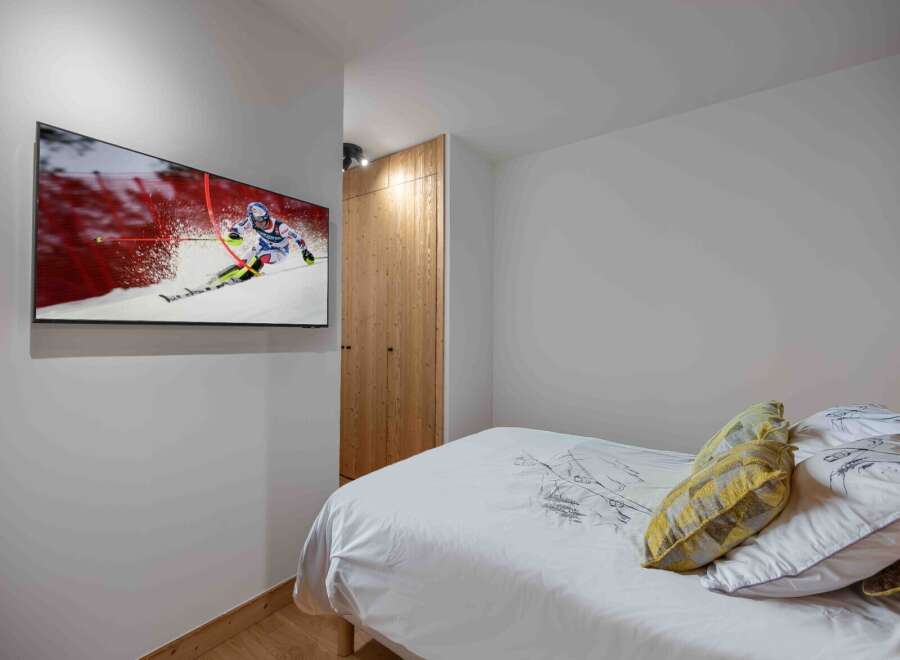 This cozy bedroom features a modern design with a mounted TV, perfect for entertainment.