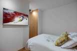 This cozy bedroom features a modern design with a mounted TV, perfect for entertainment.
