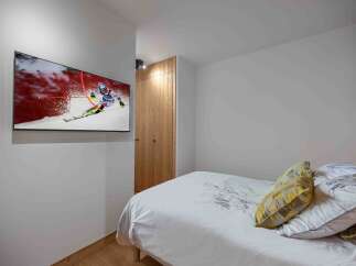 This cozy bedroom features a modern design with a mounted TV, perfect for entertainment.