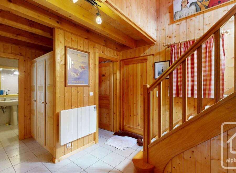 Step into this inviting chalet entrance, showcasing warm wooden paneling and a charming staircase.