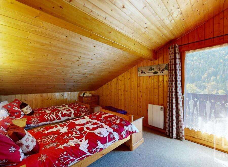 Discover the charm of this cozy bedroom featuring a warm wooden interior and a stunning view.